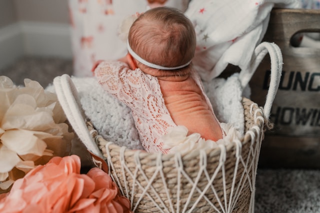 newborn baby lying in a woven basket with floral decorations and soft blankets